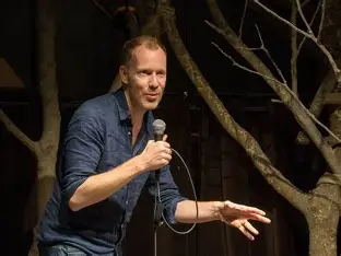 David Galle tijdens een live comedyshow, waar hij het publiek vermaakt met zijn scherpe humor en energieke aanwezigheid